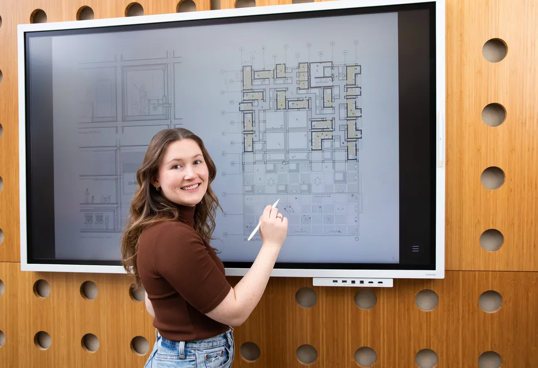 Alumni MaryKate Krege from the school of Architecture sketching on a board.